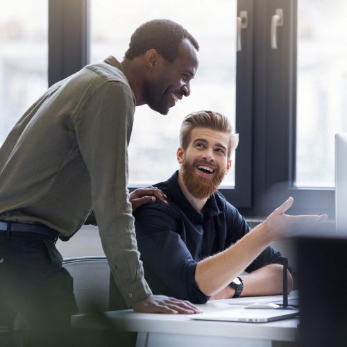 Two happy men working together on a new business project Two happy smiling men working together on a new business project at a workplace